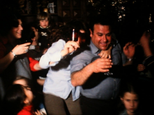 Un grupo de personas se divierten bailando y bebiendo. Al fondo se ven adornos navideños.